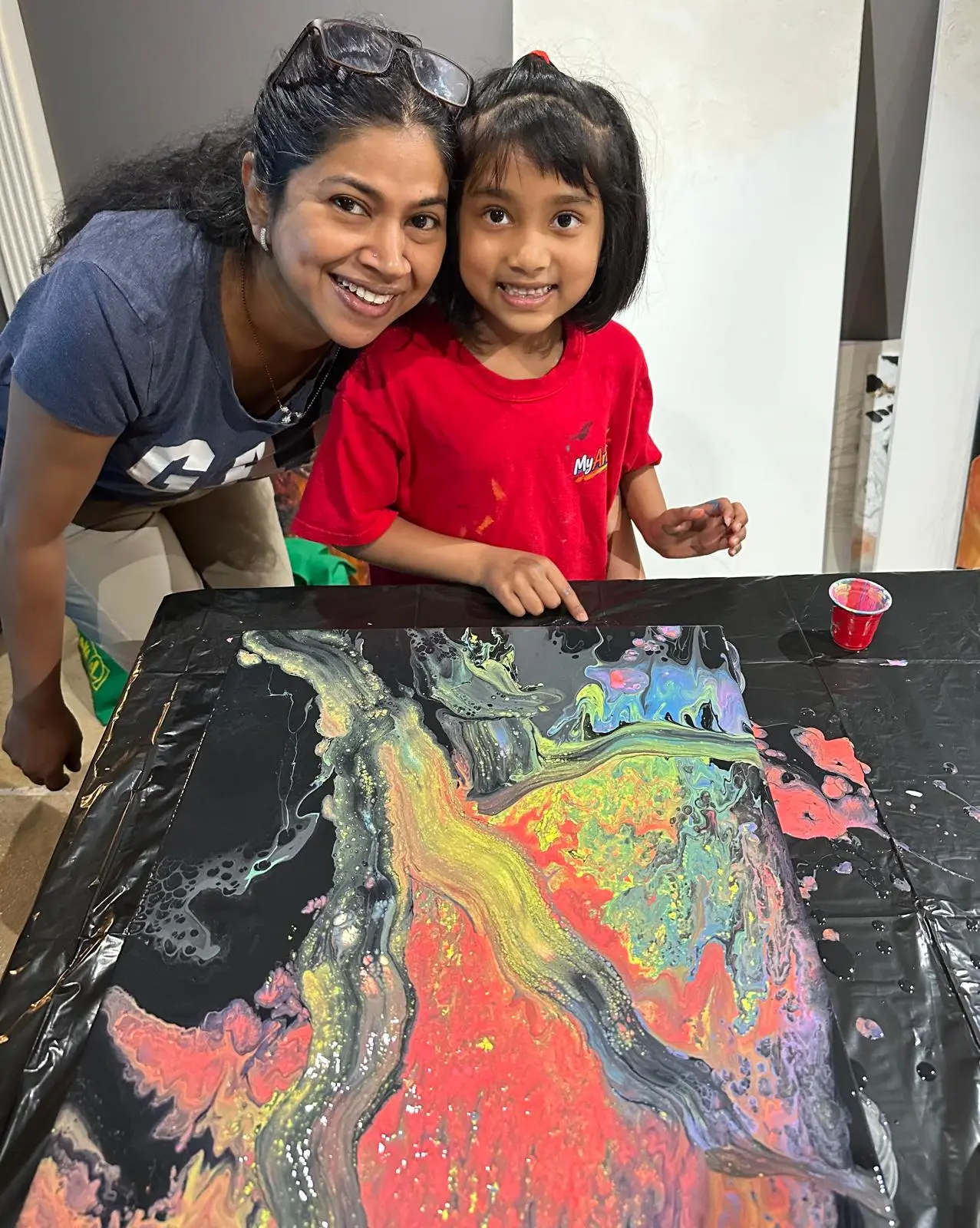 Parent and child with a pour painting in the studio