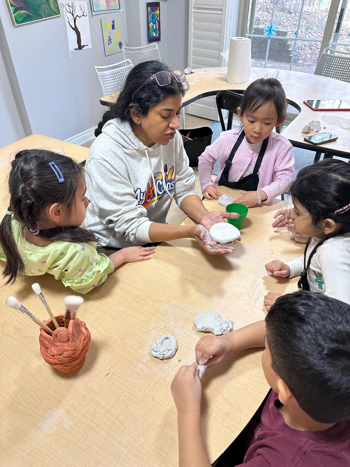Shri working with children on a clay project in the studio